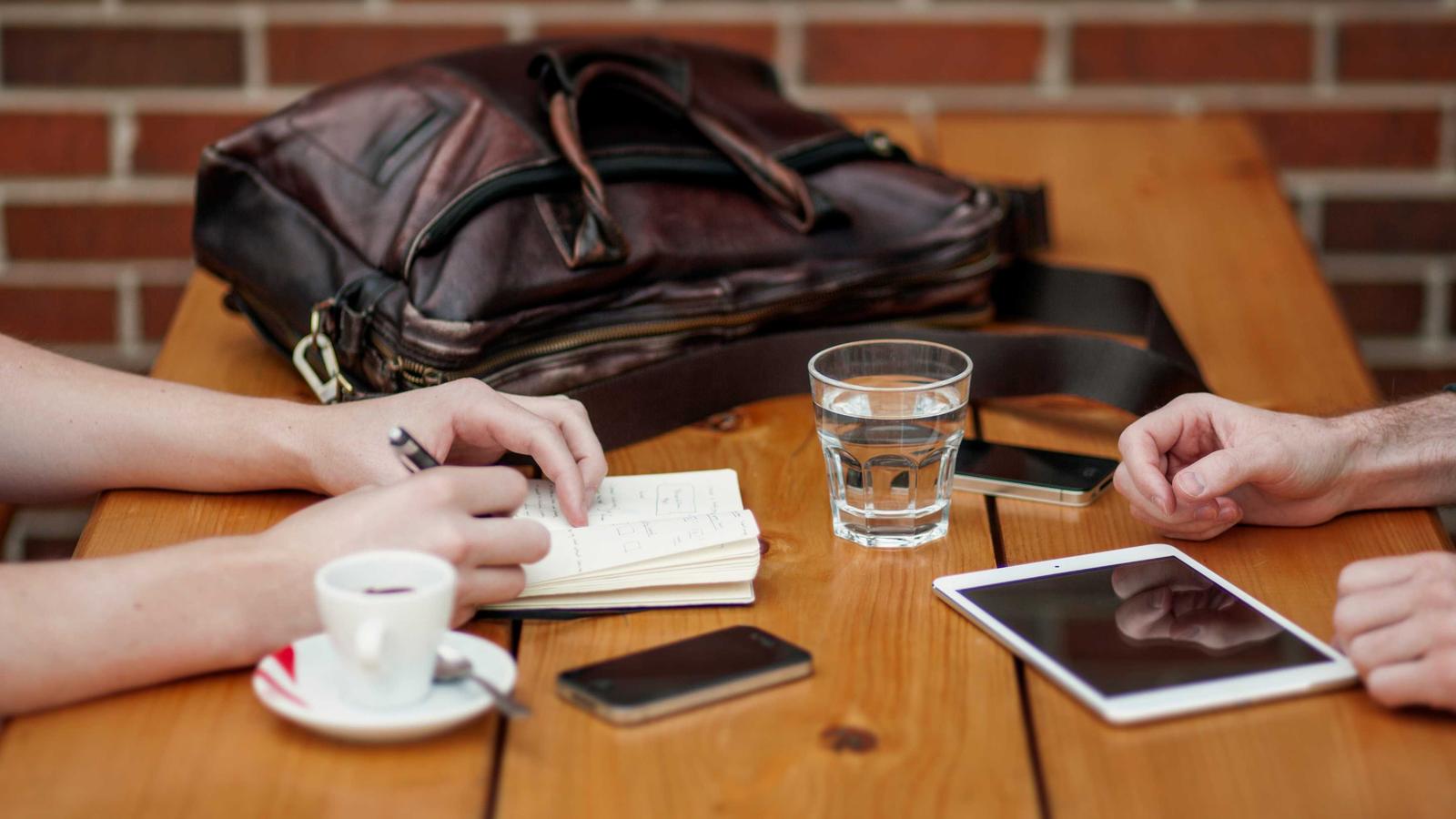 Two people reviewing notes and a tablet across a table