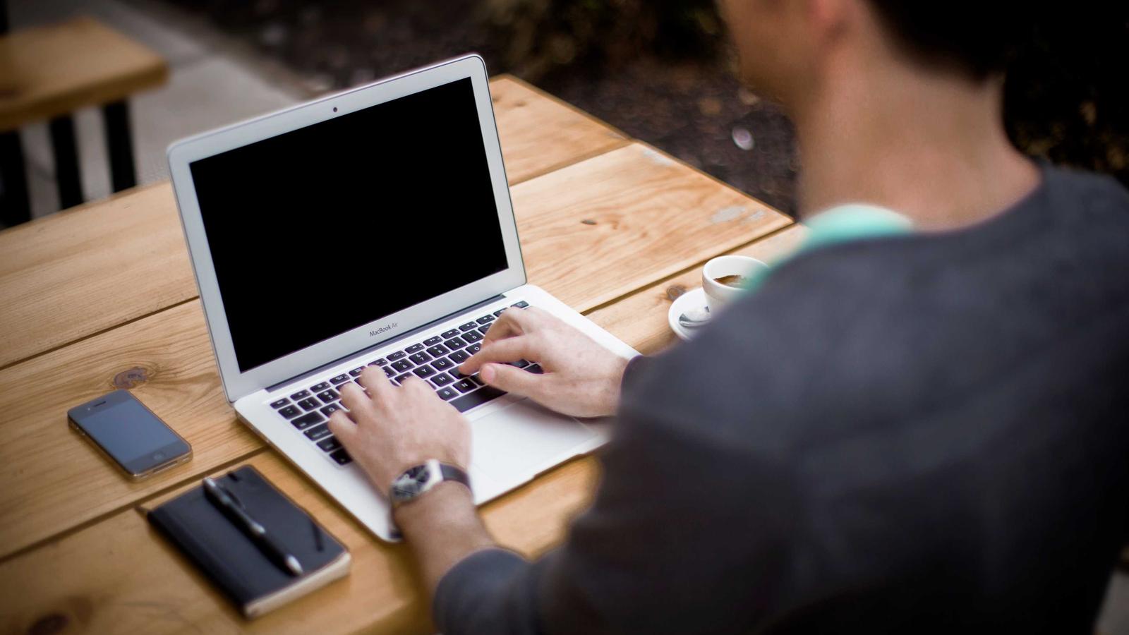Someone typing on a laptop at a wooden desk