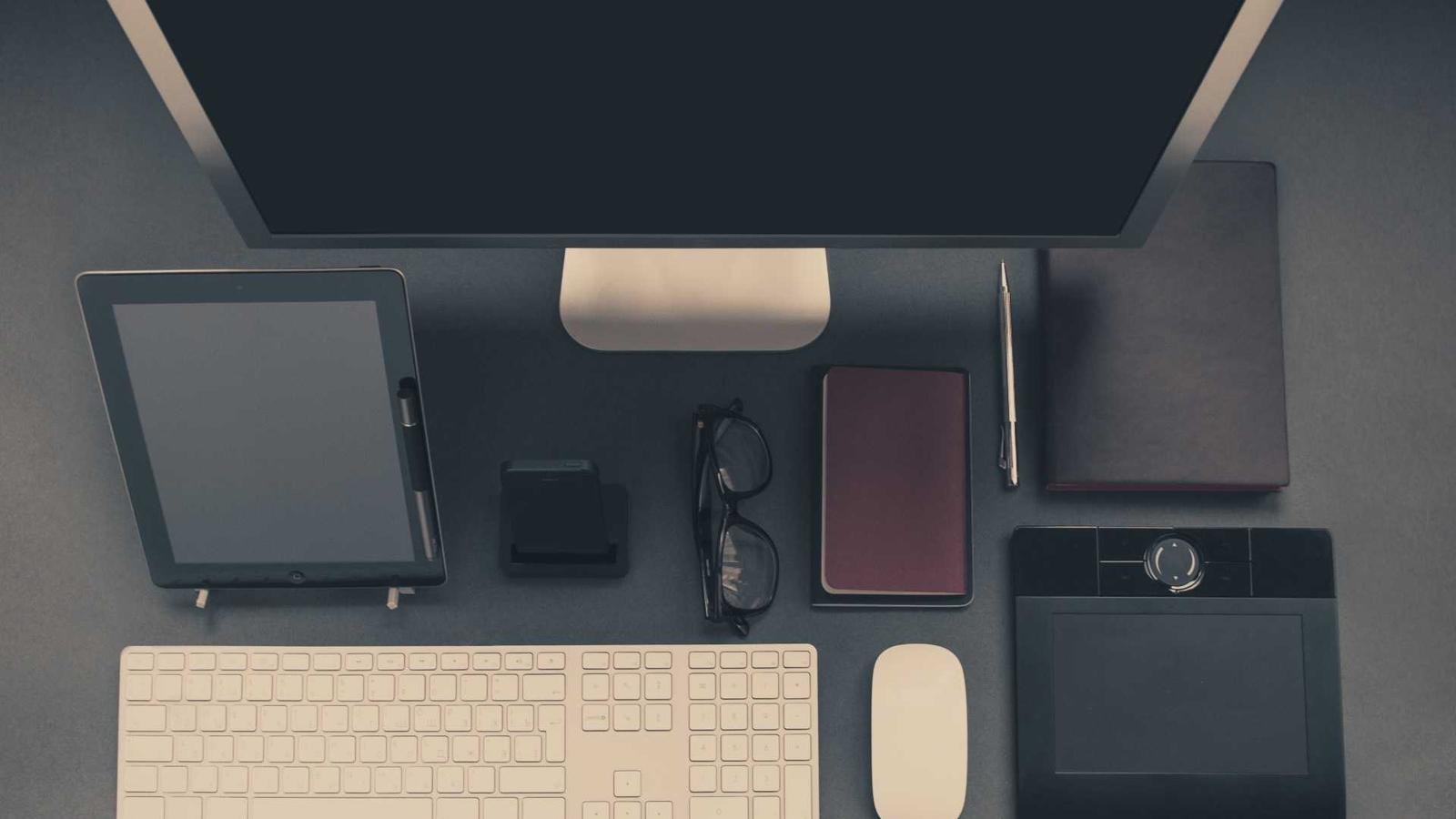 A tidy desk with a monitor, keyboard and notebook