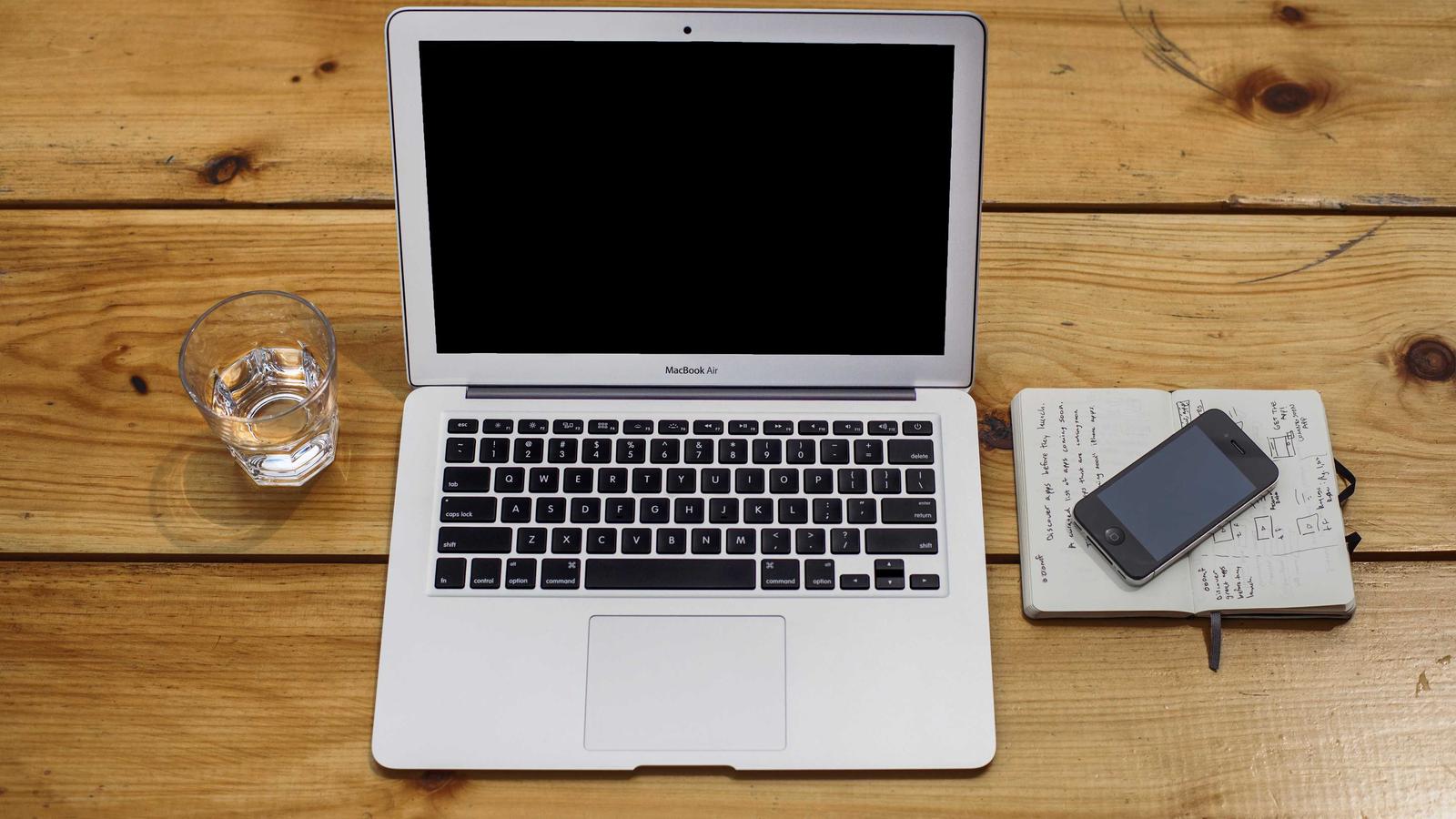 Laptop, phone and coffee on a wooden table, seen from above