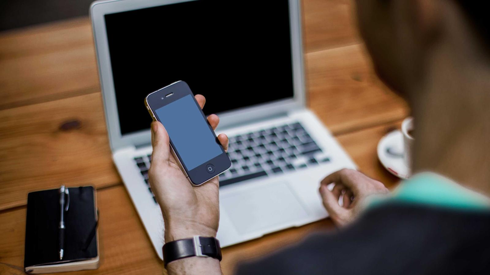Phone and laptop on a wooden desk